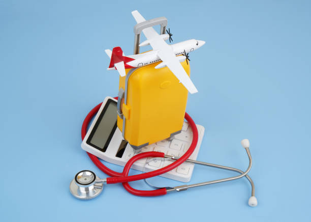 istock Airplane model, calculator and stethoscope with orange suitcase on blue background. 2166325784