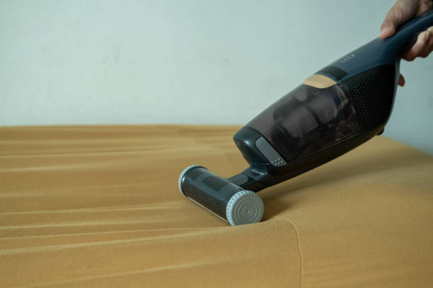istock Asian woman's hands using vacuum cleaner on sofa 2166328389