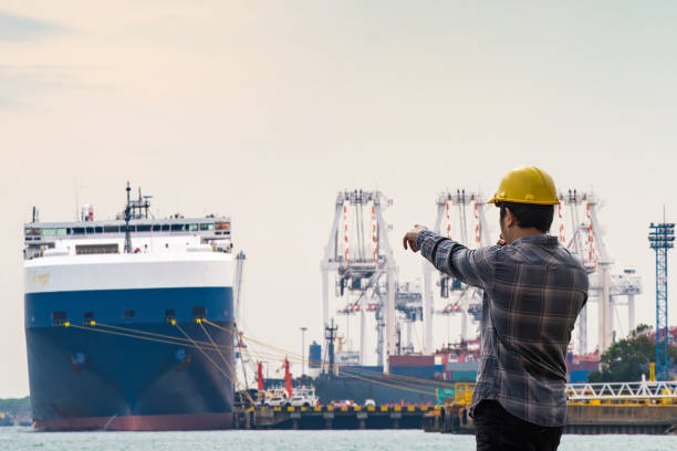 istock Worker directing cargo ship at busy port 2166330969