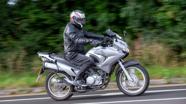 Potterspury,Northants,UK - Aug 11th 2024: Man riding a silver 2010 Honda XL 125 V-9 motorcycle travelling on a British road