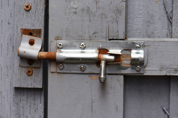 Rusty galvanised sliding bolt lock on a wooden back garden gate or back gate door or entrance. Grey and silver colour. day outdoors. Close up.