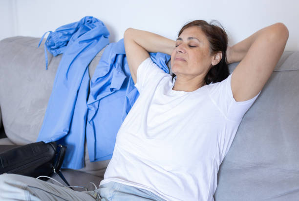 istock nurse medical worker resting and taking a break sitting cross-legged on the sofa after work. 2166335116