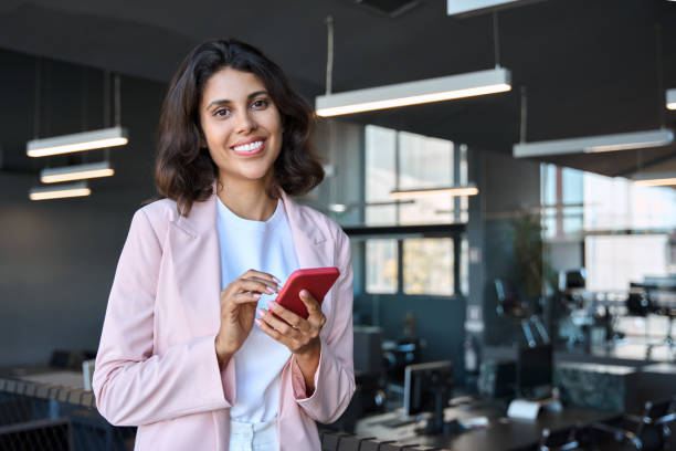 istock Portrait young business woman manager using cell phone mobile app for call, communication. Latin Hispanic female businesswoman holding smartphone for online work, looking at camera standing in office 2166344687