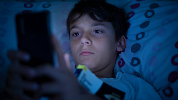 istock Boy with insomnia uses smartphone in bed before going to sleep due to sleep problems 2166350594