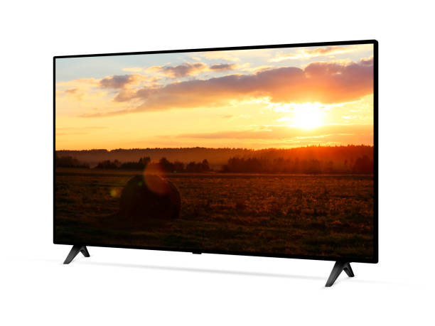 Flat screen TV from angled view with rural landscape with straw roll and sunset sky on screen