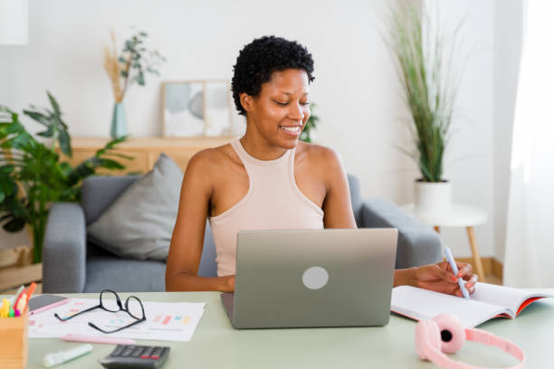 istock Young black woman working from home taking notes and smiling 2166354540