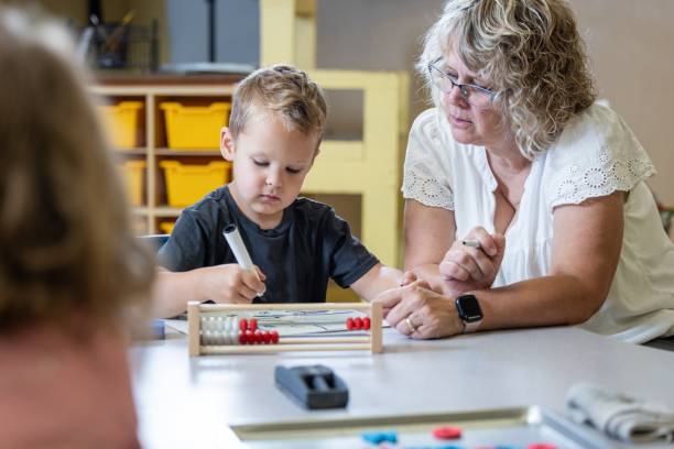 istock A young boy is sitting at a table with his teacher teaching him math 2166355317