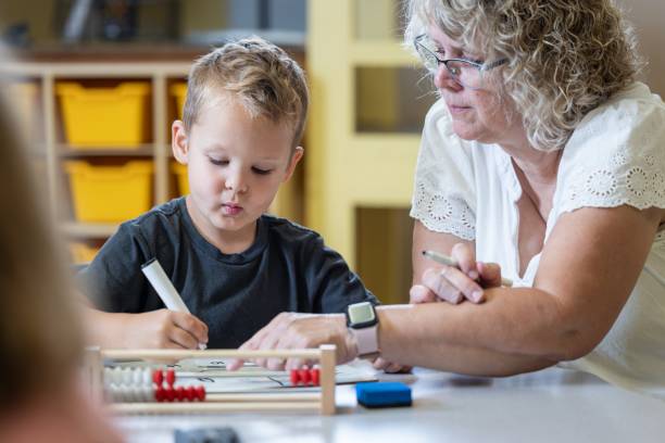 istock A young boy is sitting at a table with his teacher teaching him math 2166355404