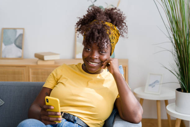 istock Woman using smartphone while relaxing on couch at home 2166355485
