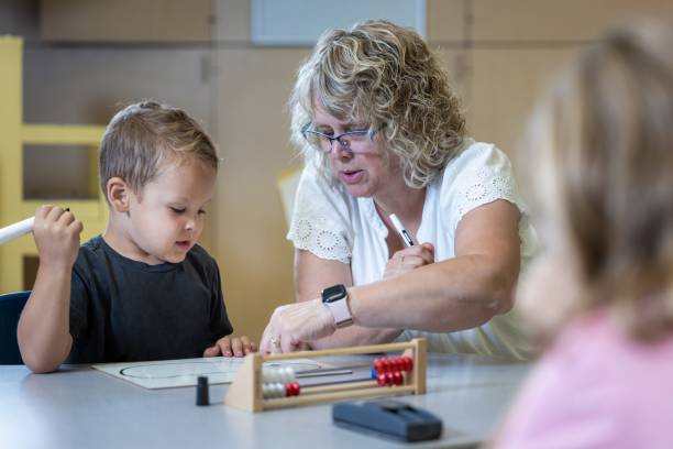 istock A young boy is sitting at a table with his teacher teaching him math 2166355692