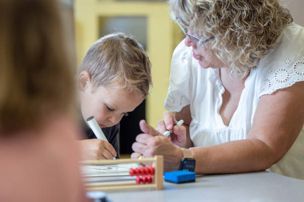 istock A young boy is sitting at a table with his teacher teaching him math 2166355806