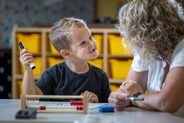 istock A young boy is sitting at a table with his teacher teaching him math 2166356907
