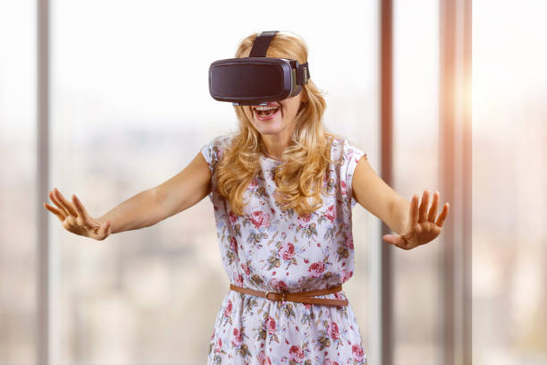 istock Amazed happy young woman experiences virtual reality stretch her arms. 2166358795