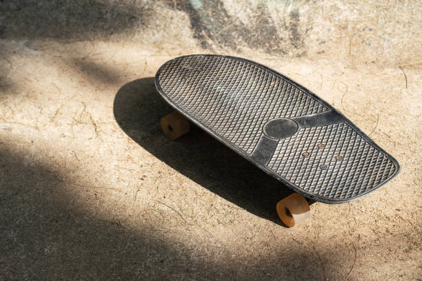 istock Skateboard on Sunlit Concrete Road with Tree Shadows 2166359819