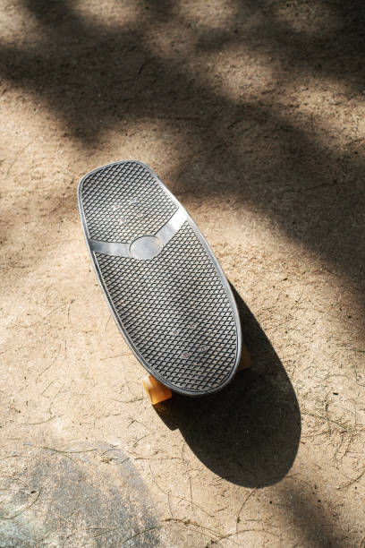 istock Skateboard on Sunlit Concrete Road with Tree Shadows 2166359844