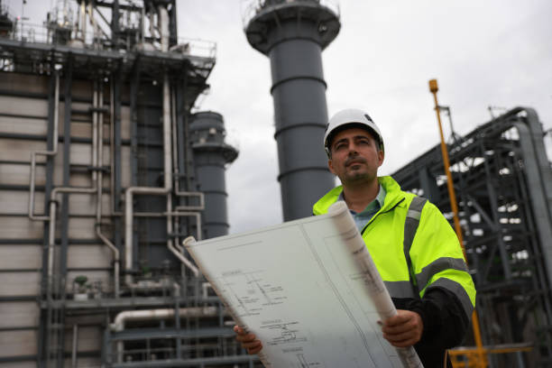 istock System  engineer with glow green safety jacket holds blueprint drawing at Thermal  Power plant power manufacturing site 2166360077
