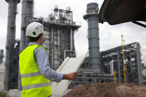 istock Electrical engineers, holding blueprints, look confident at the thermal power plant while working on project planning to produce high-voltage electrical energy, emphasizing the energy concept. 2166360178