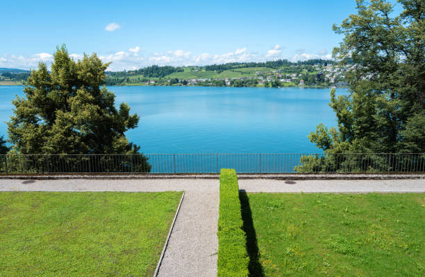 Tranquil lakeside scene in Rapperswil with lush greenery and blue sky. Negative space.