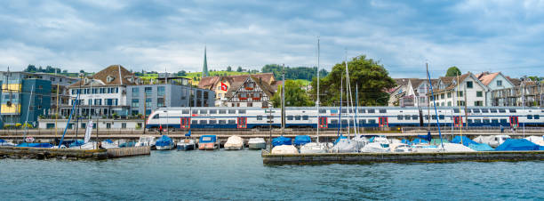 Wadenschwil, Switzerland - July 1, 2024: A Swiss Railways train passes the marina in Wadenswil on Lake Zurich