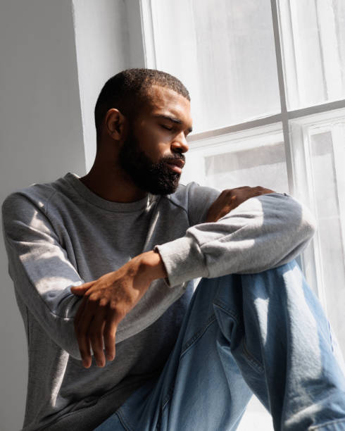 istock African american man sitting in sunlight near window 2166362999