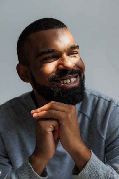 Smiling african american man with sunlight on face isolated on grey