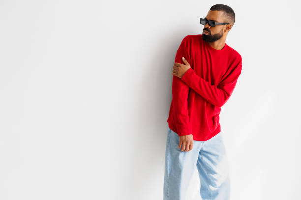 istock Young african american man in sunglasses and red pullover posing on grey background 2166363231