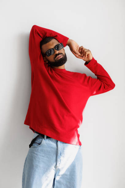istock Stylish black man in sunglasses and red pullover posing on grey background 2166363280