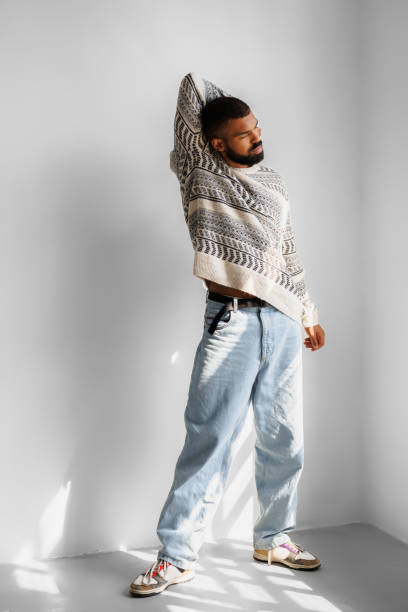 istock Young african american man in sweater and jeans posing in studio 2166363488