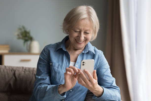 istock Smiling elderly woman using cell phone seated on couch 2166371909