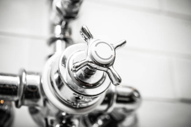 A sleek, modern chrome faucet handle gleams in a well-lit bathroom, perfect for kitchen and bathroom redesign. An essential component for contemporary plumbing aesthetics.