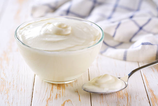 istock Greek yogurt or sour-cream in a bowl with spoon on a light background, selective focus. 2166374384