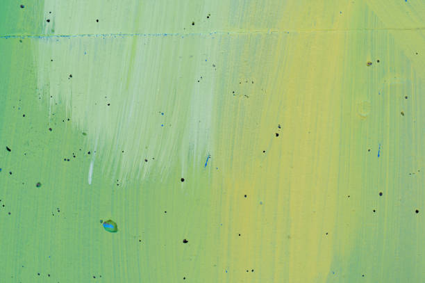 Close-up of an abstract surface with green and yellow brushstrokes, accented by small holes. The image showcases the varied textures and vibrant colors, creating a dynamic and artistic composition.