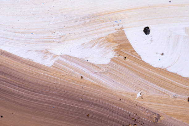 Close-up of an abstract surface featuring beige and white brushstrokes. The image captures the textured patterns and subtle color gradients, creating a soft and flowing visual effect that emphasizes the intricate brushwork.