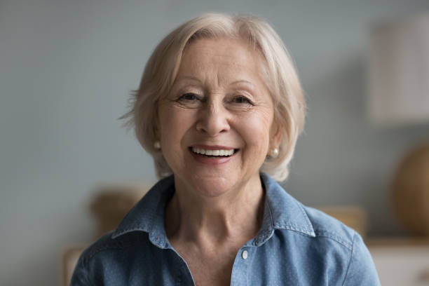 Head shot portrait happy retired woman staring at camera Head shot portrait happy beautiful retired woman. Mature female advertises professional services of dental clinic smile look at camera. Carefree life on retirement, medical insurance cover for seniors senior women stock pictures, royalty-free photos & images