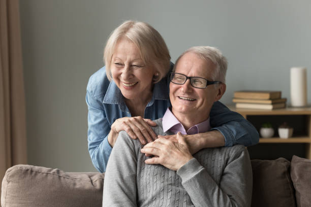 istock Senior wife hugs his husband resting on sofa at home 2166376556