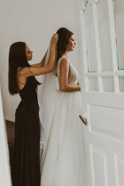istock A bridesmaid helps the bride put on her veil. 2166380849