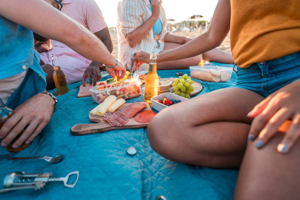 istock Multi-Ethnic People Eating Snacks and Drinking Beer While On A Beach Picnic 2166383357