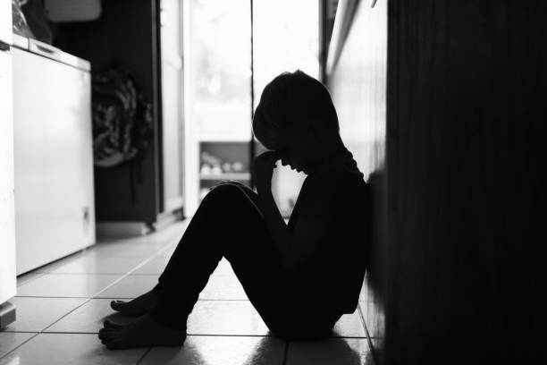 istock Sad little lonely boy sitting on the ground at home. 2166389350