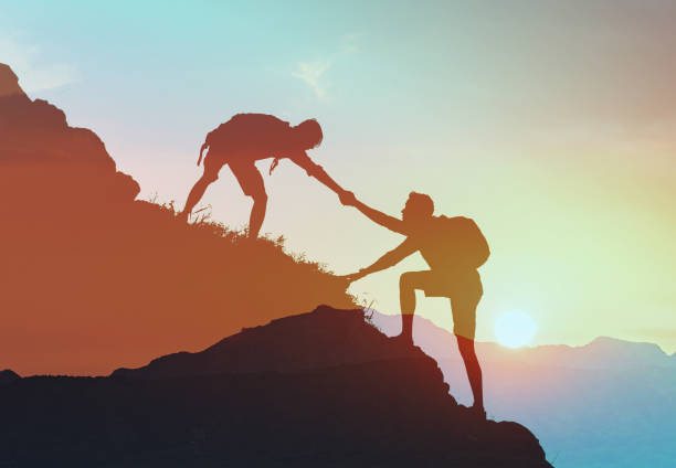 istock Hikers helping each other climb up a mountain working as a team. 2166389537