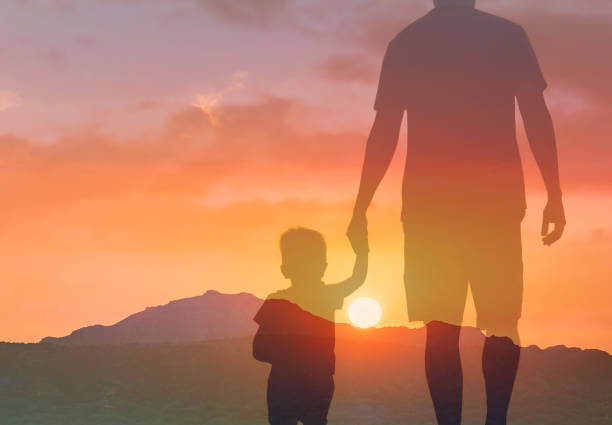 istock Father and his son holding hands walking at sunset 2166389795