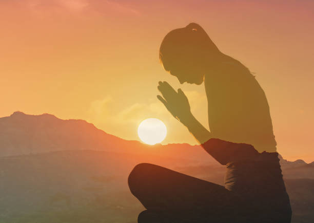 istock Woman praying at sunset. 2166389987