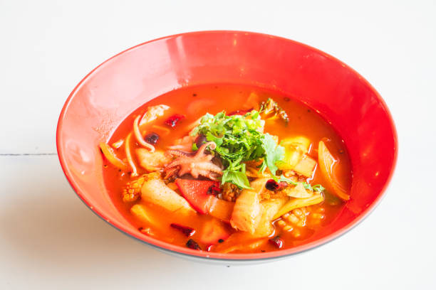 A vibrant bowl of spicy seafood soup garnished with fresh cilantro, featuring pieces of octopus, shrimp, and various vegetables.