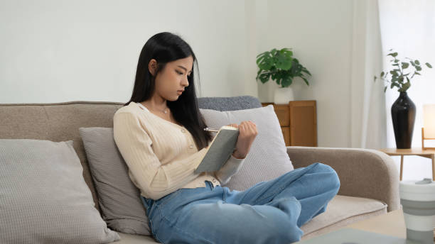 istock Young asian women reading the book to analysis information and writing notes while sitting on comfortable couch to learning self-study and spending time to relaxation with enjoying lifestyle at home 2166398206