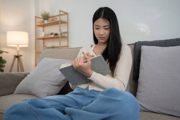 istock Young asian women reading a book to researching educational and taking notes while sitting on comfortable couch to learning self-study and spending time to relaxation with enjoying lifestyle at home 2166398215