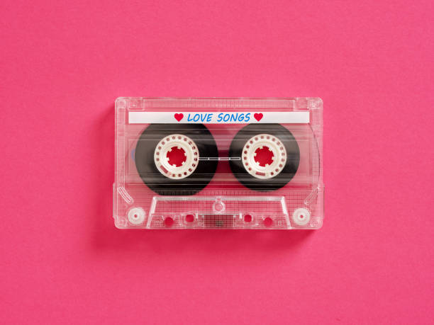 Transparent audio cassette tape lying on pink background Music and love songs concept. Transparent audio cassette tape with magnetic recording band lying on a pink background. mix tape heart stock pictures, royalty-free photos & images