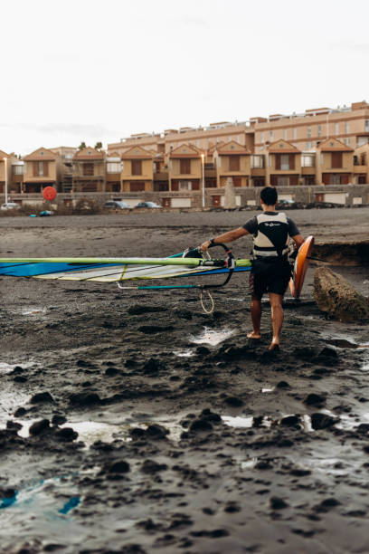 very brave sporty man practicing extreme sport called Kitesurfing on a windy day above a very rough ocean with high waves