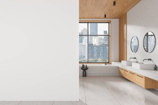 istock Hotel bathroom interior with double sink and bathtub, window. Mockup wall 2166413616