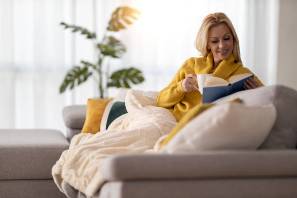 istock Woman reading book on sofa at home 2166415255