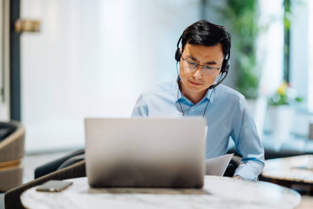 istock Asian businessman on videoconference with headset in modern office, capture the serious and contemplative emotions. 2166416912