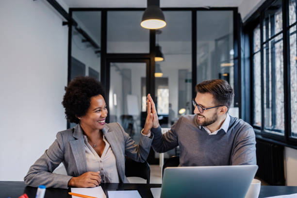 Happy interracial coworkers giving high five for teamwork at boardroom.